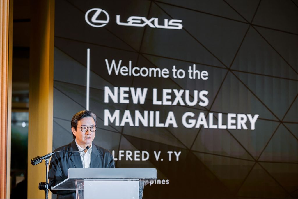 A speaker at a lectern beneath a screen reading Welcome to the New Lexus Manila Gallery.